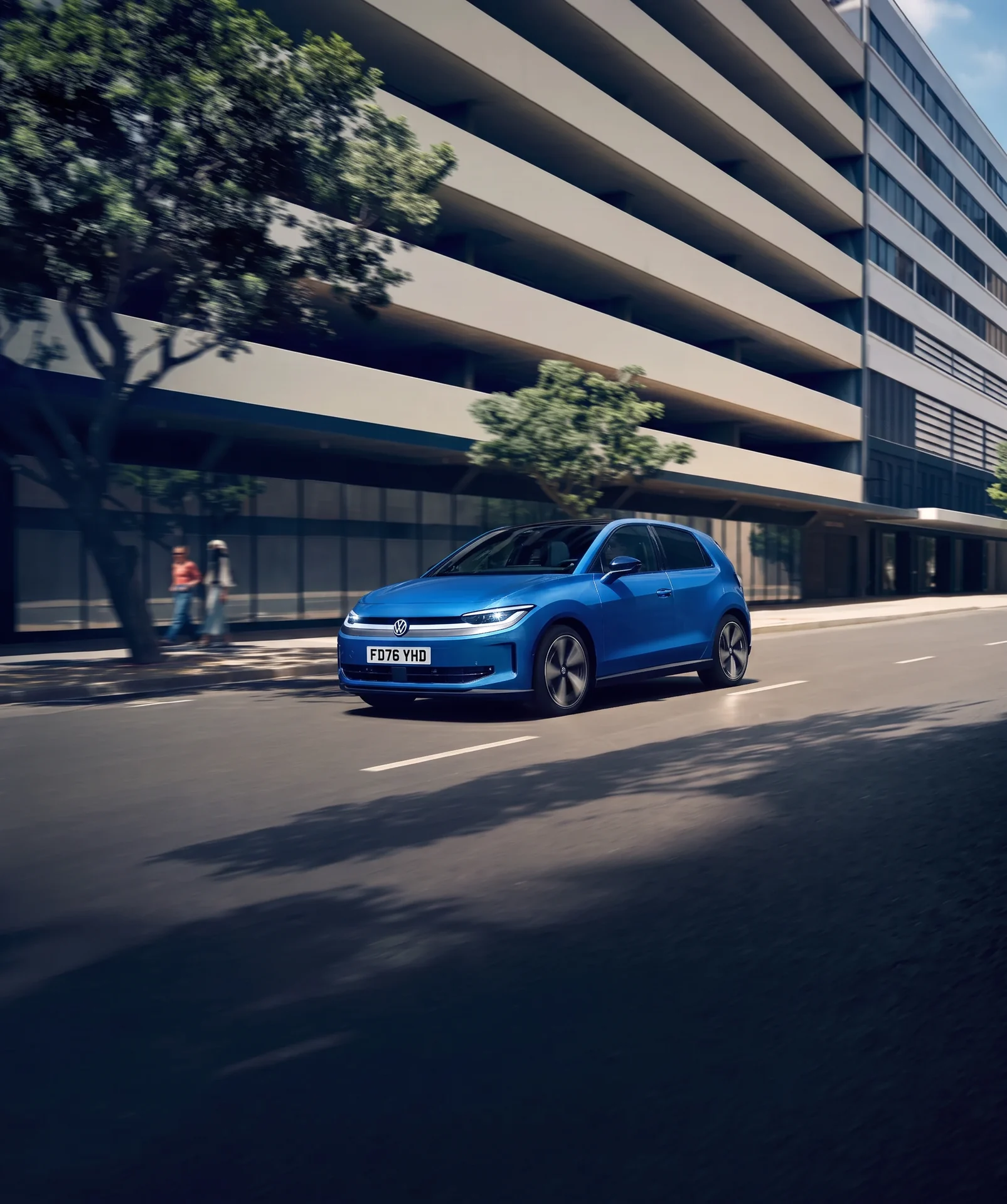 Blue Volkswagen ID. Polo travelling along an urban road beside a modern building