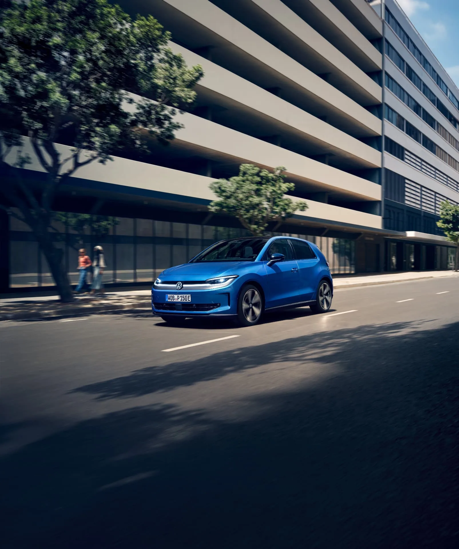 Blue Volkswagen ID. Polo travelling along an urban road beside a modern building